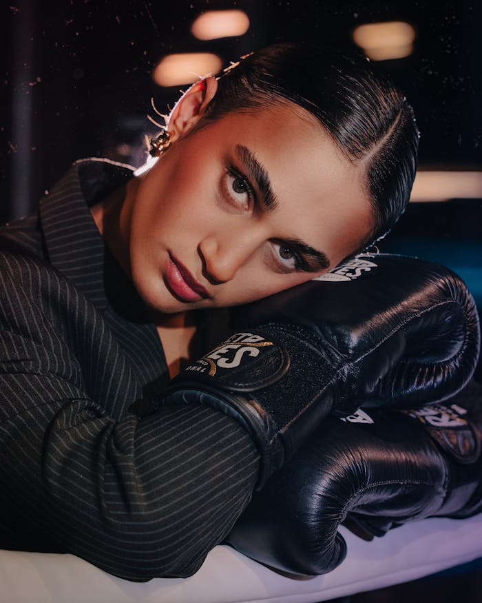 Home Striking portrait of a woman resting on her boxing gloves, showcasing strength and style.